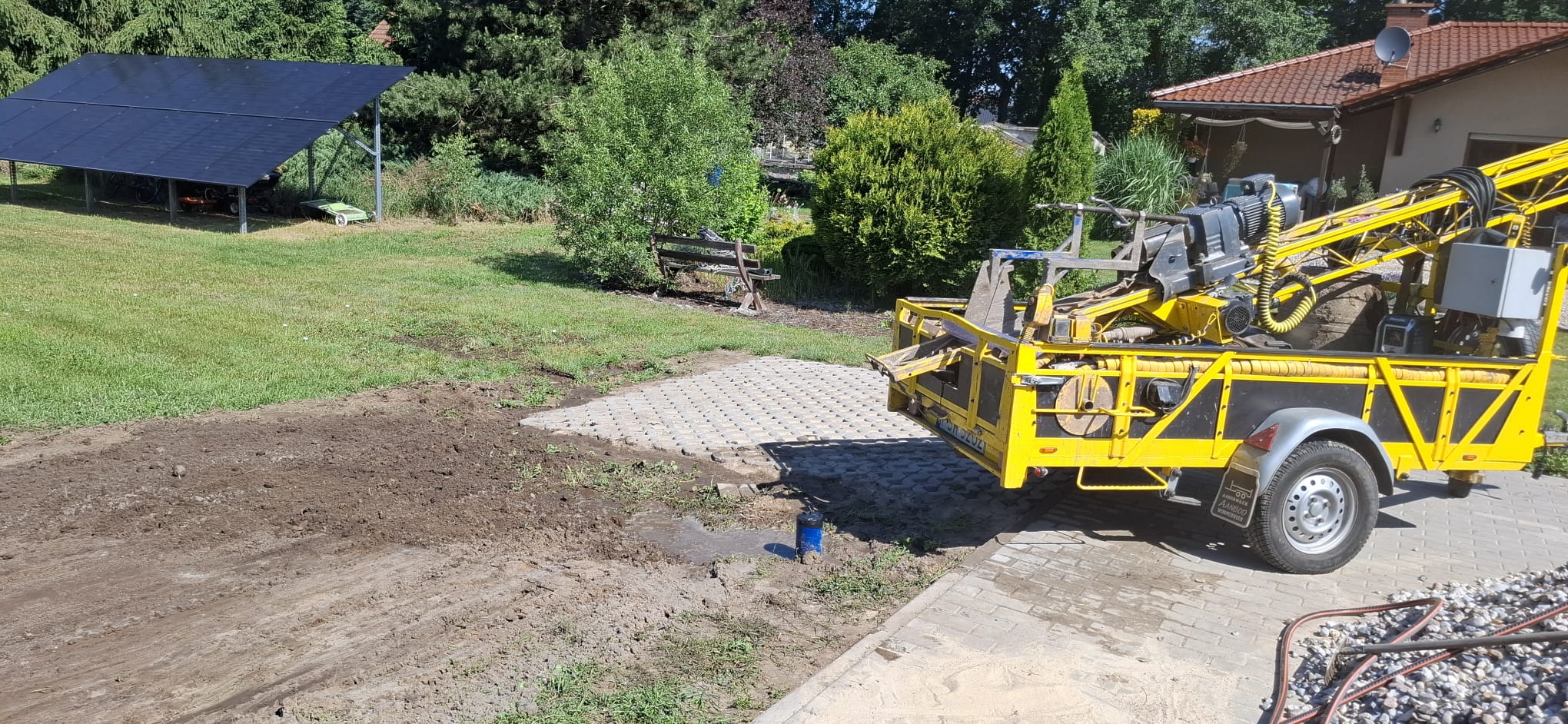 Kompaktowa żółta wiertnica Muro-Metalplast na zagospodarowanej posesji